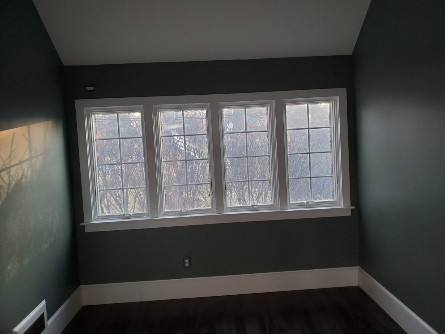 Four windows with white trim in a room.