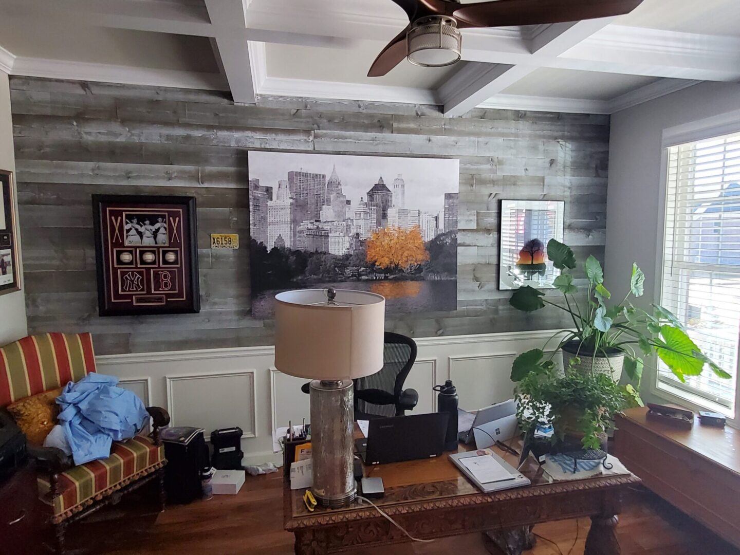 Home office with wood panel wall and city art.