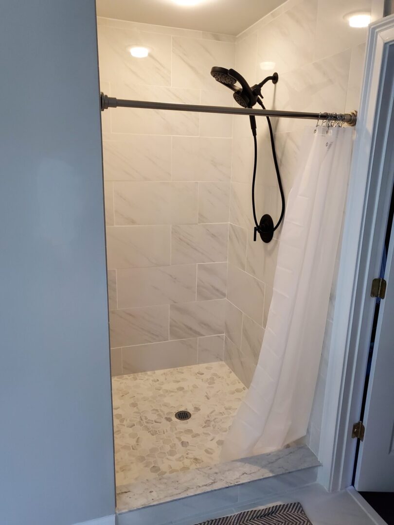 White tiled shower with a shower curtain.