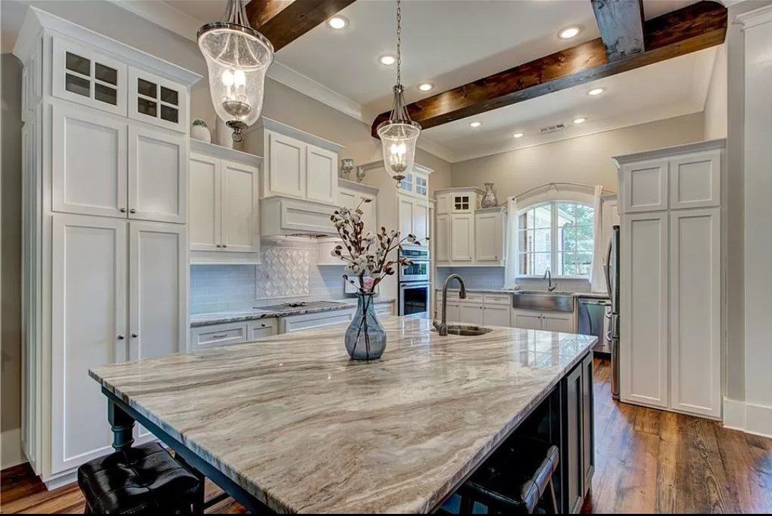 Kitchen island with granite countertop and white cabinets.
